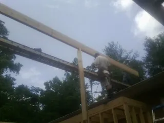 Carpenter setting a ridge beam over a new addition frame — Ice Dam Removal by Roofing Brothers in Guyton