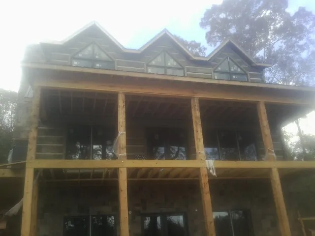 Dormers and porch framing on a large log home under construction — Roof Coating work by our crew in Guyton
