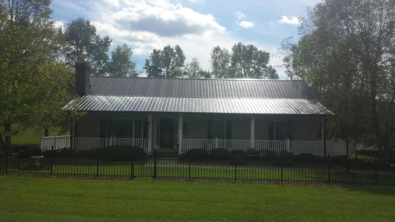 Gray metal roof on a brick ranch with a full width front porch — Gutter Guard Installation work by our crew in Guyton