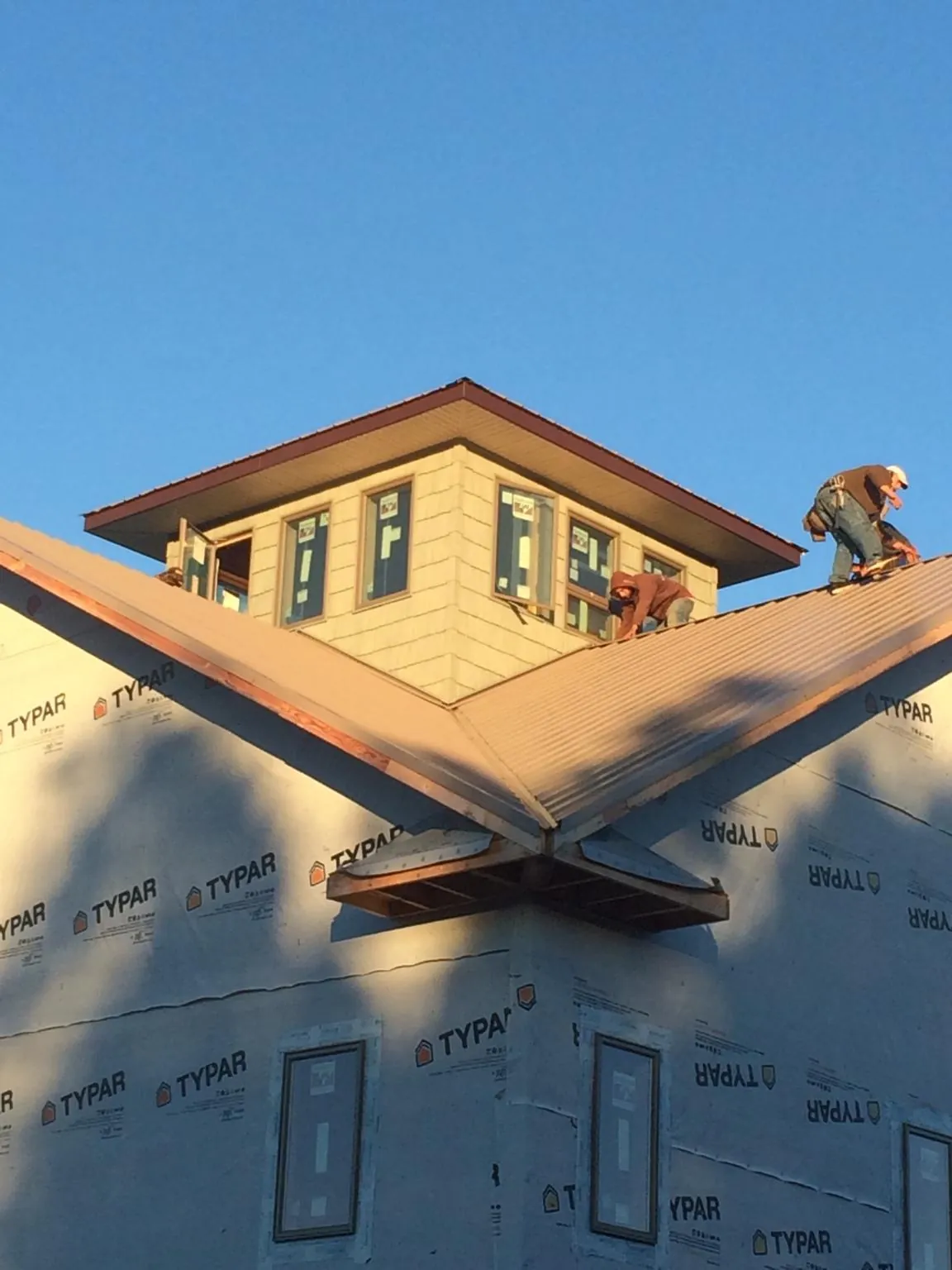 Roofers working around a rooftop cupola on a new metal roof at sunset — Roof Waterproofing in Guyton by Roofing Brothers